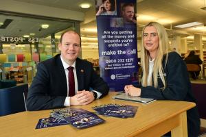 Communities Minister Gordon Lyons attends a Make the Call outreach event in Carrickfergus Library to announce the Make the Call annual results for 2023/24. Pictured with Department for Communities’ Make the Call outreach officer Julie Taylor. Make the Call event 