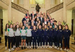 Minister Deirdre Hargey in the Great Hall in Parliament Buildings with members of the Antrim Camogie and Ladies Gaelic Football teams